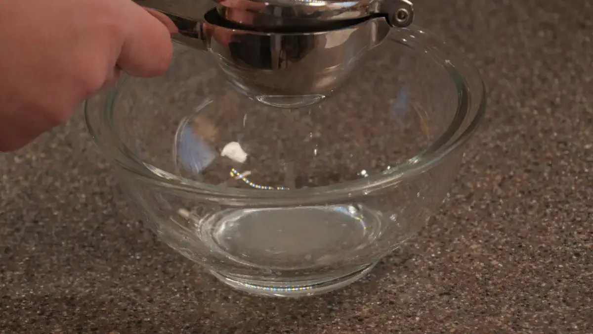 Person using a hand juicer over a glass bowl