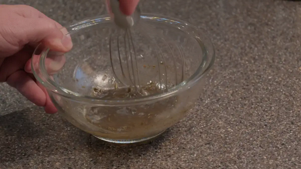 Person using a hand whisker in a glass bowl
