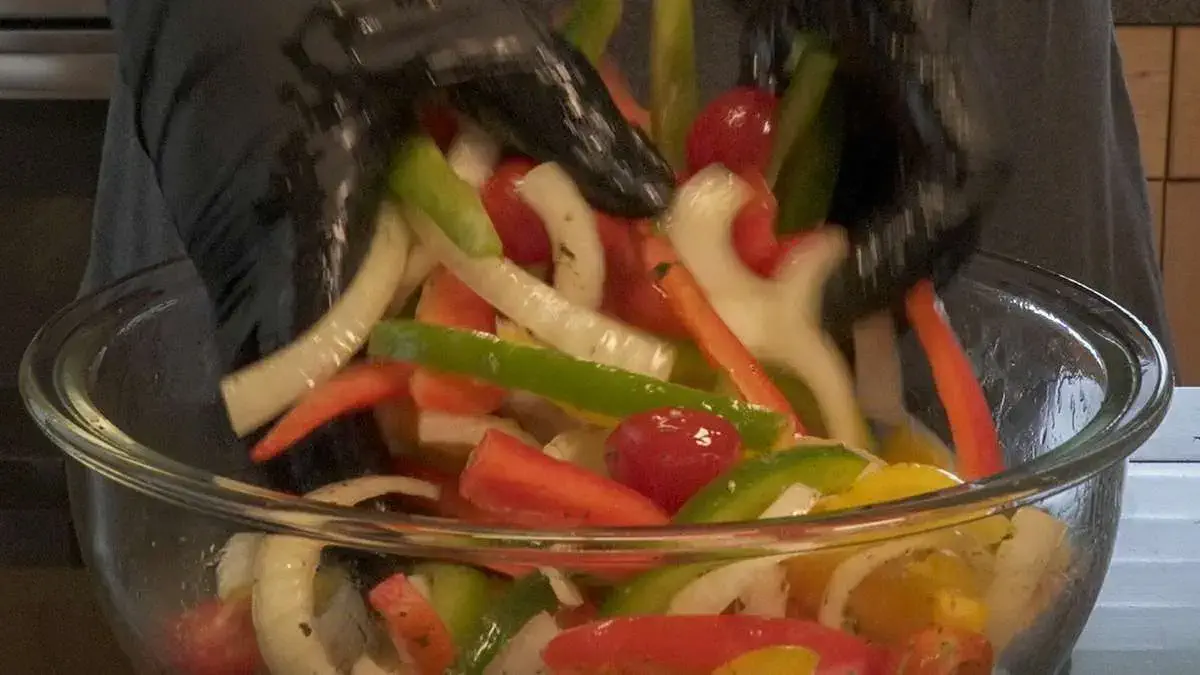 Close-up of a two hands tossing the ingredients in a bowl