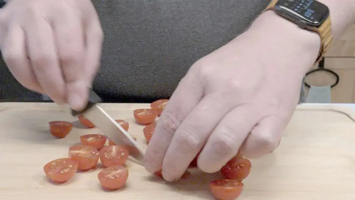 Person cutting cherry tomatoes in half with a knife